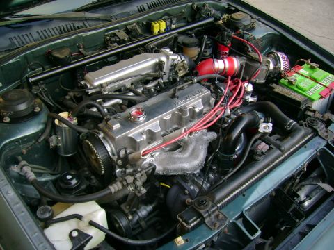 1989 Mazda MX-6 - Engine bay view showing aftermarket modifications including an intake system and polished valve cover.