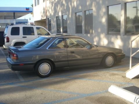 1989 Mazda MX-6 - This 1989 Mazda MX-6 coupe is seen parked in a lot next to an SUV.