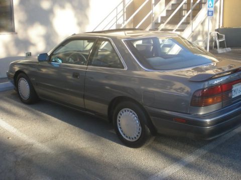 1989 Mazda MX-6 - A gray Mazda MX-6 is parked in a lot, showing its rear passenger side and part of the interior.