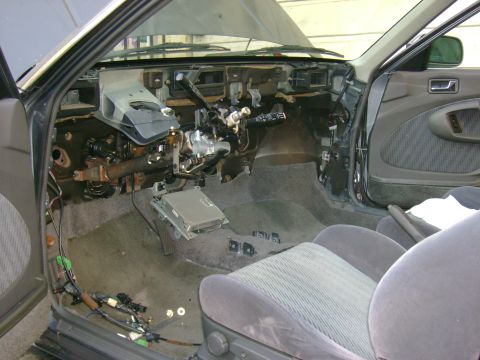 1989 Mazda MX-6 - The interior of a 1989 Mazda MX-6 shows extensive disassembly of the dashboard and center console.