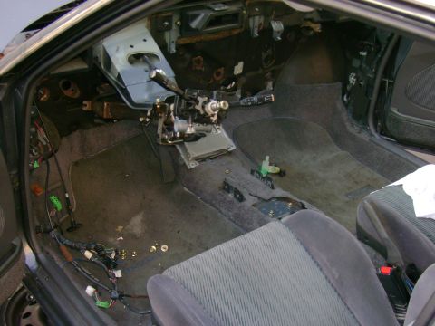 1989 Mazda MX-6 - The interior of a car is shown with the dashboard disassembled and wiring exposed, indicating repair or modification work.