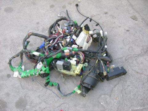 1989 Mazda MX-6 - A complex automotive wiring harness is spread out on a gray concrete surface, showing numerous wires and electrical components.