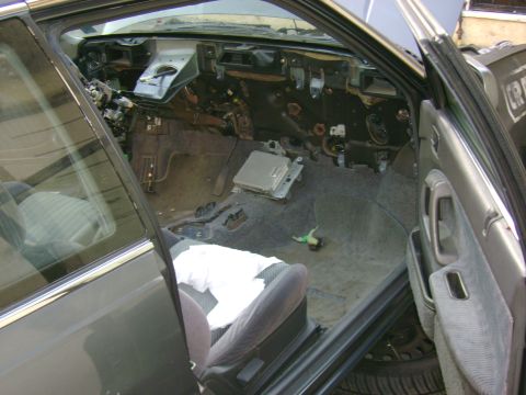 1989 Mazda MX-6 - The interior of a car is shown with the dashboard disassembled, revealing exposed wiring and parts.