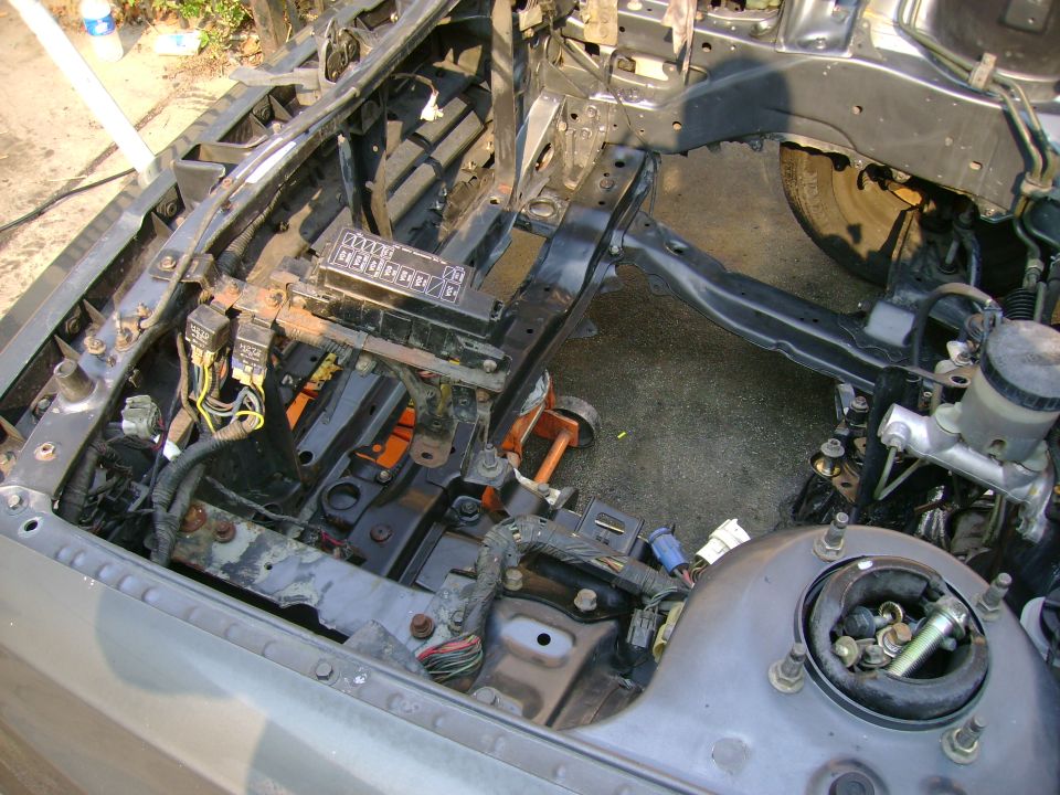 Car engine bay showing fuse box, wiring harnesses, and master cylinder