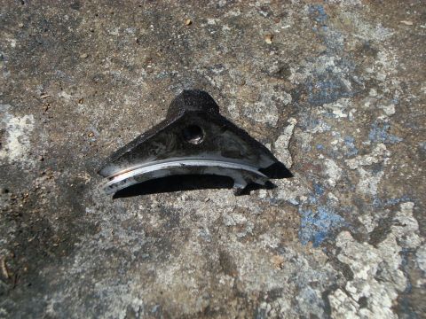 1986 Ford Bronco - A detached metal component, possibly from a vehicle, lies on a textured concrete surface.
