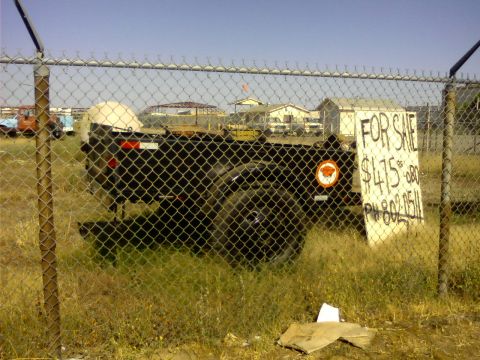 1989 Ford Bronco - A trailer is for sale behind a chain-link fence, with a sign detailing the price and phone number.