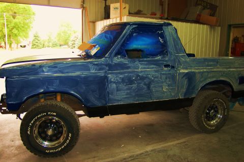 1989 Ford Bronco - This blue Ford Bronco is in a garage, covered in primer and tape, ready for paint.