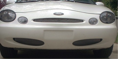 1997 Ford Taurus - The front end of a white Ford Taurus is shown, its distinctive grille and headlights.