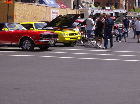 1970 Ford Ranchero - Two classic Chevrolet Camaros, a red convertible and a yellow coupe, are displayed at an outdoor car show.