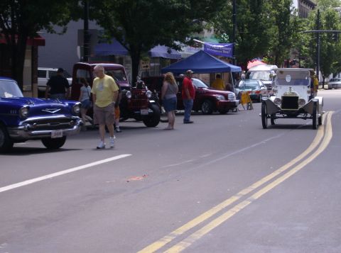 1970 Ford Ranchero - A vintage Model T Ford is seen from the front at an outdoor car show with other vehicles present.