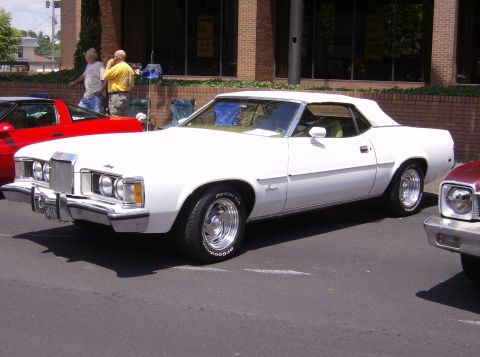 1970 Ford Ranchero - A white convertible coupe with a tan top is parked next to a red car and a maroon car.