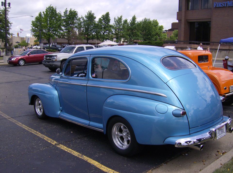 Blue sedan with chrome trim and aftermarket wheels, seen from the rear quarter angle