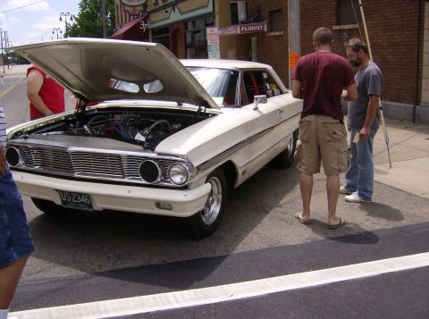 1970 Ford Ranchero - A classic Ford with its hood up, parked on a street with people around.