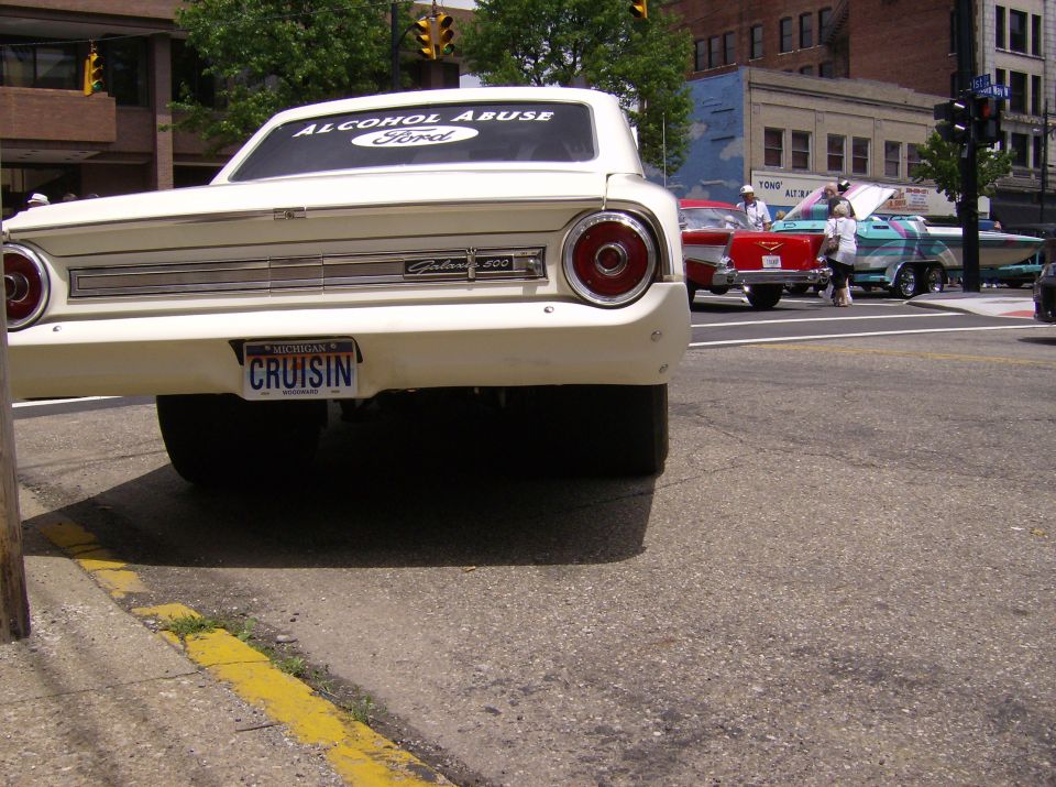 Rear view of a 1964 Ford Galaxie 500 with a 'CRUISIN' license plate. Other cars visible in background