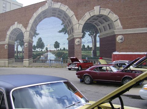 1970 Ford Ranchero - Several classic cars are parked in front of a large brick building with a mural.
