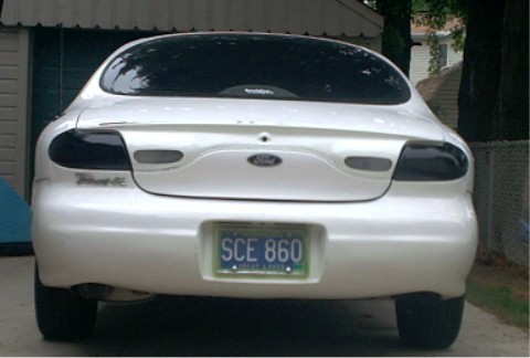 1997 Ford Taurus - The rear of a white 1997 Ford Taurus is shown, tinted taillights and a license plate.