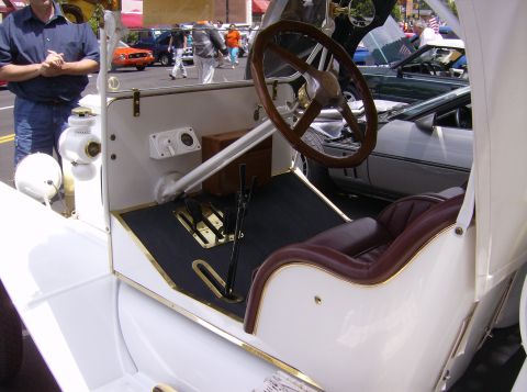 1970 Ford Ranchero - The interior of a classic white car features a wooden steering wheel, burgundy upholstery, and a visible brake pedal assembly.