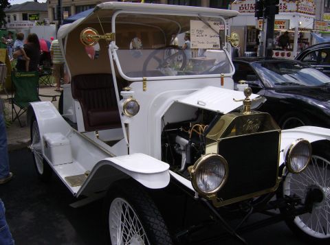 1970 Ford Ranchero - Antique white Ford Model T touring car on display at an outdoor event, with a modern car visible behind.