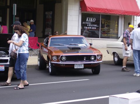 1970 Ford Ranchero - This orange 1970 Ford Mustang Mach 1 is parked on a street, likely at a car show.