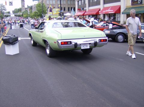 1970 Ford Ranchero - A light green muscle car is seen from the rear at a street car show with spectators.