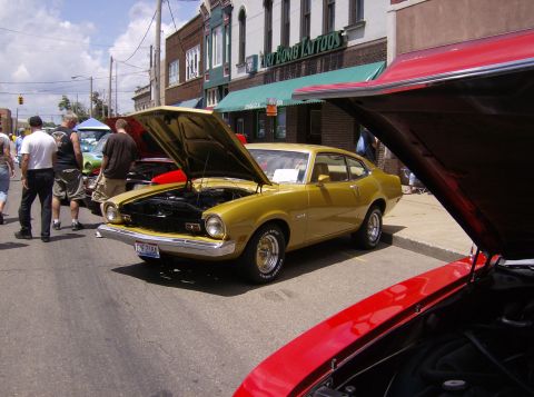 1970 Ford Ranchero - A gold 1970 Ford Maverick coupe is displayed with its hood open at a street car show.