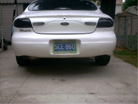 1997 Ford Taurus - The rear of a white Ford Taurus is parked on a concrete driveway. The license plate is visible.