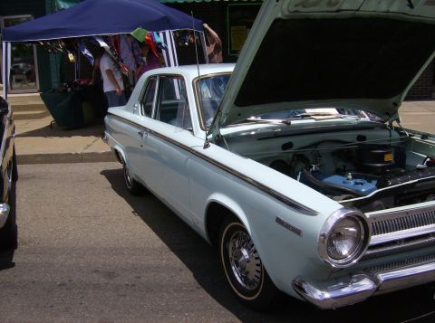 1970 Ford Ranchero - A light blue sedan is displayed with its hood open at an outdoor event.