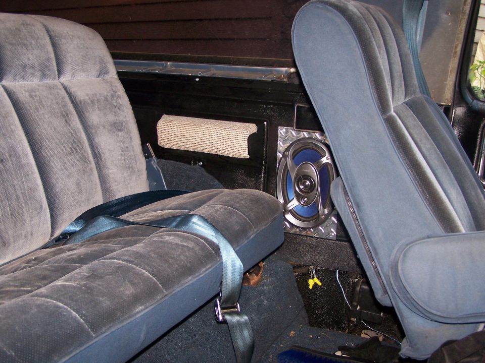 Vehicle interior showing gray cloth rear seats and a speaker mounted on the side panel
