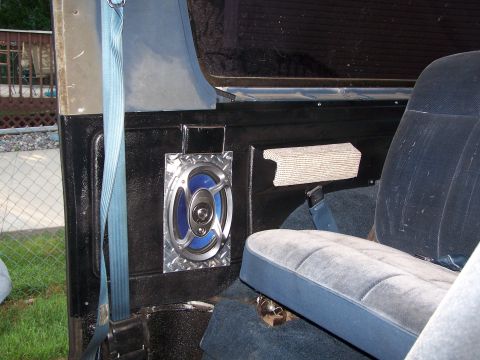 1986 Ford Bronco - The interior of a vehicle shows a speaker and a seat with a blue seatbelt.