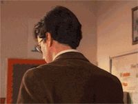 1990 Ford Bronco - A man wearing glasses and a brown jacket is viewed from the back, standing in a room with educational materials on the wall.