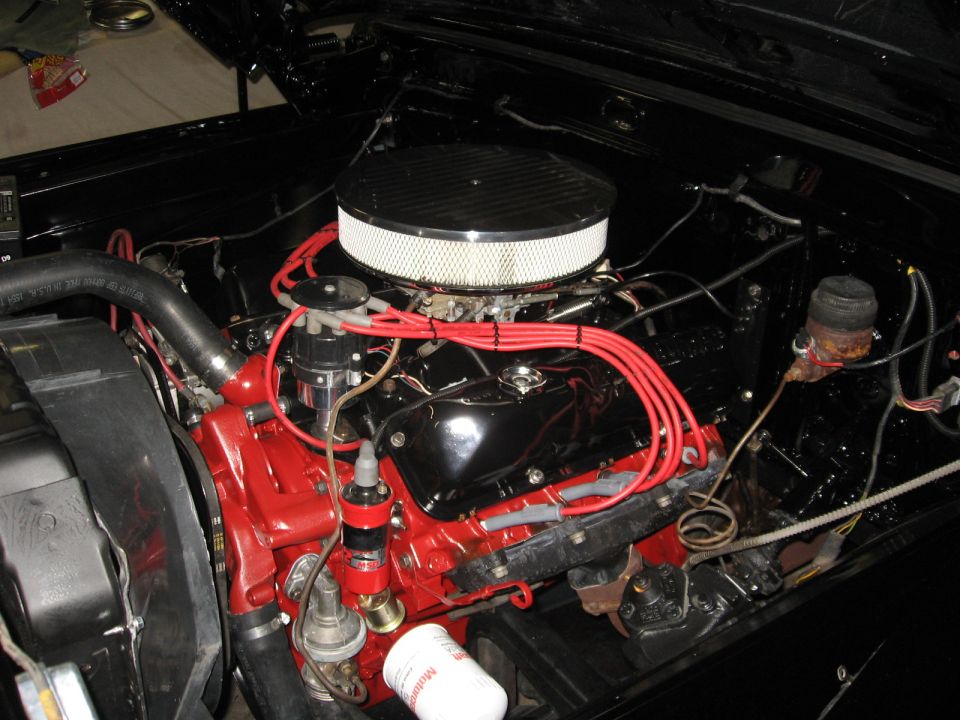 Engine bay with red block, black intake, and red spark plug wires