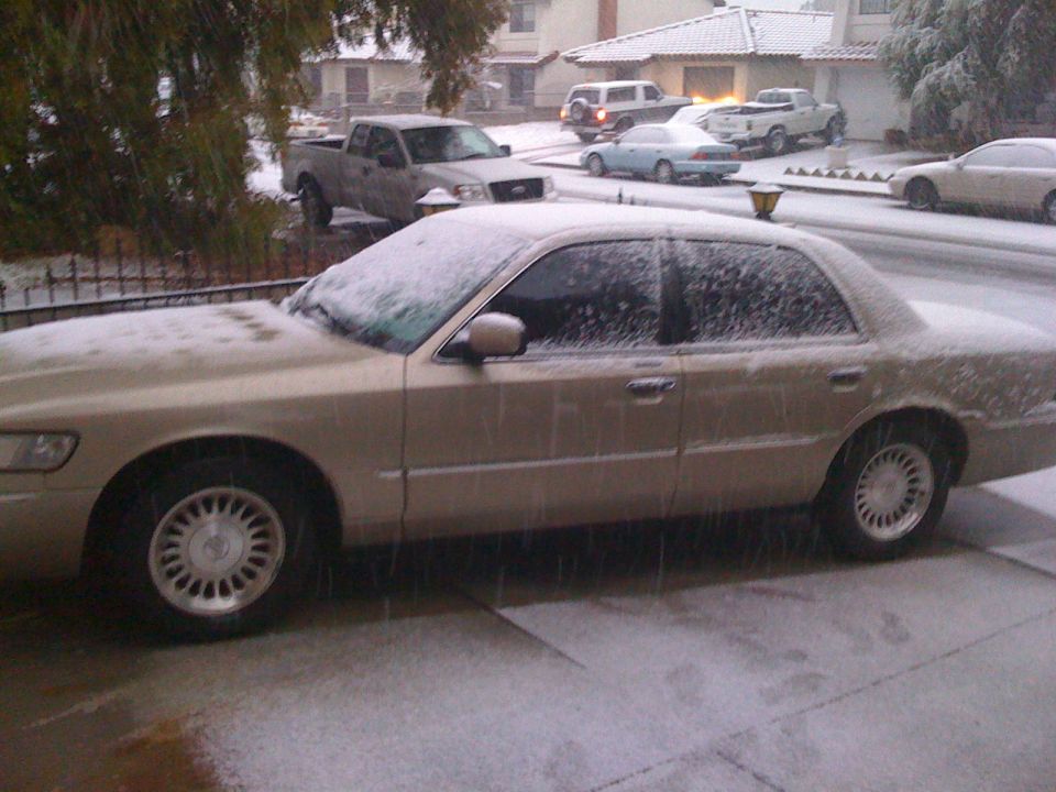 Side view of a 1999 Mercury Grand Marquis covered in snow