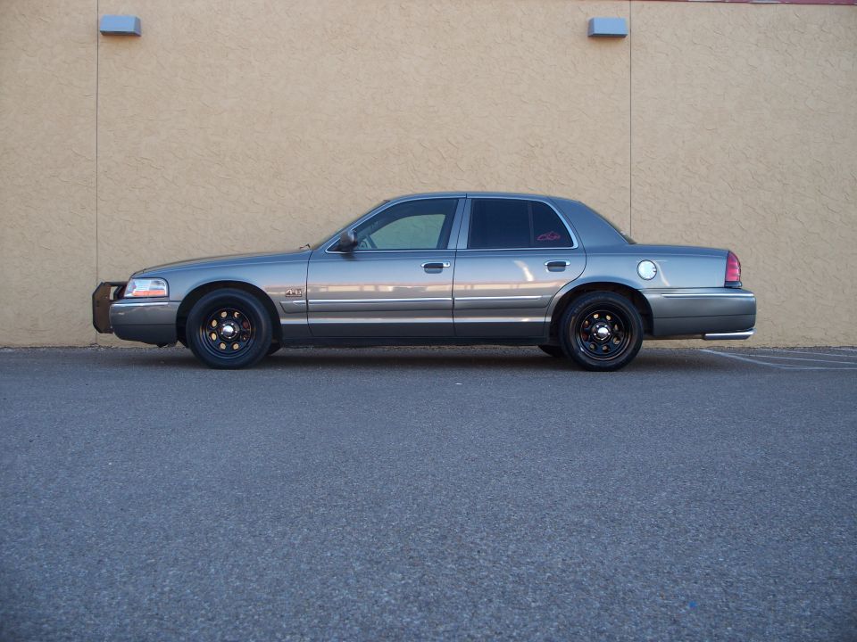 Gray 2003 Mercury Grand Marquis sedan, side view, black wheels, push bar