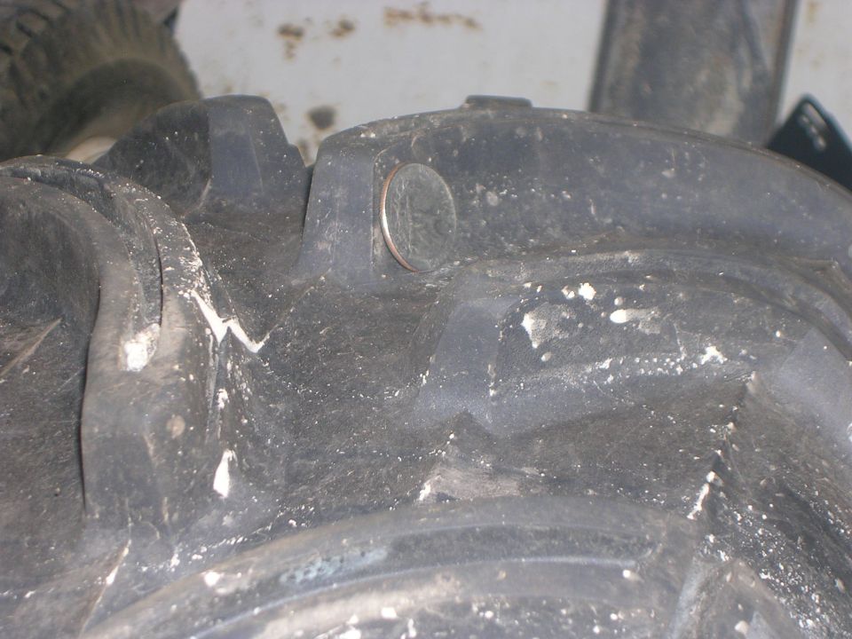 Close-up of ATV mud tire lugs with a quarter placed between them for scale