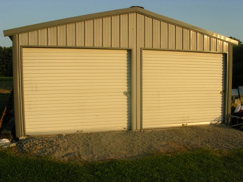 2008 Bombardier Outlander - A metal garage structure with two large roll-up doors sits under a clear sky.