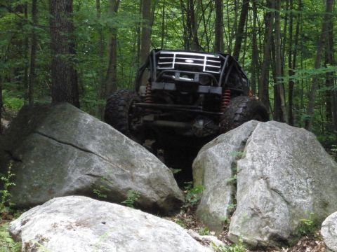 1995 Ford Bronco - Modified 1995 Ford Bronco tackling a rocky trail in the woods.