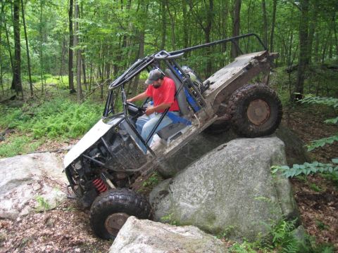 1995 Ford Bronco - A custom-built off-road buggy navigates a rocky trail in a wooded area.