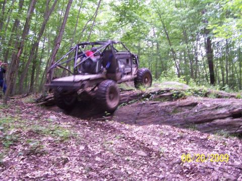 1995 Ford Bronco - Custom off-road buggy with roll cage navigating a rocky trail in the woods.