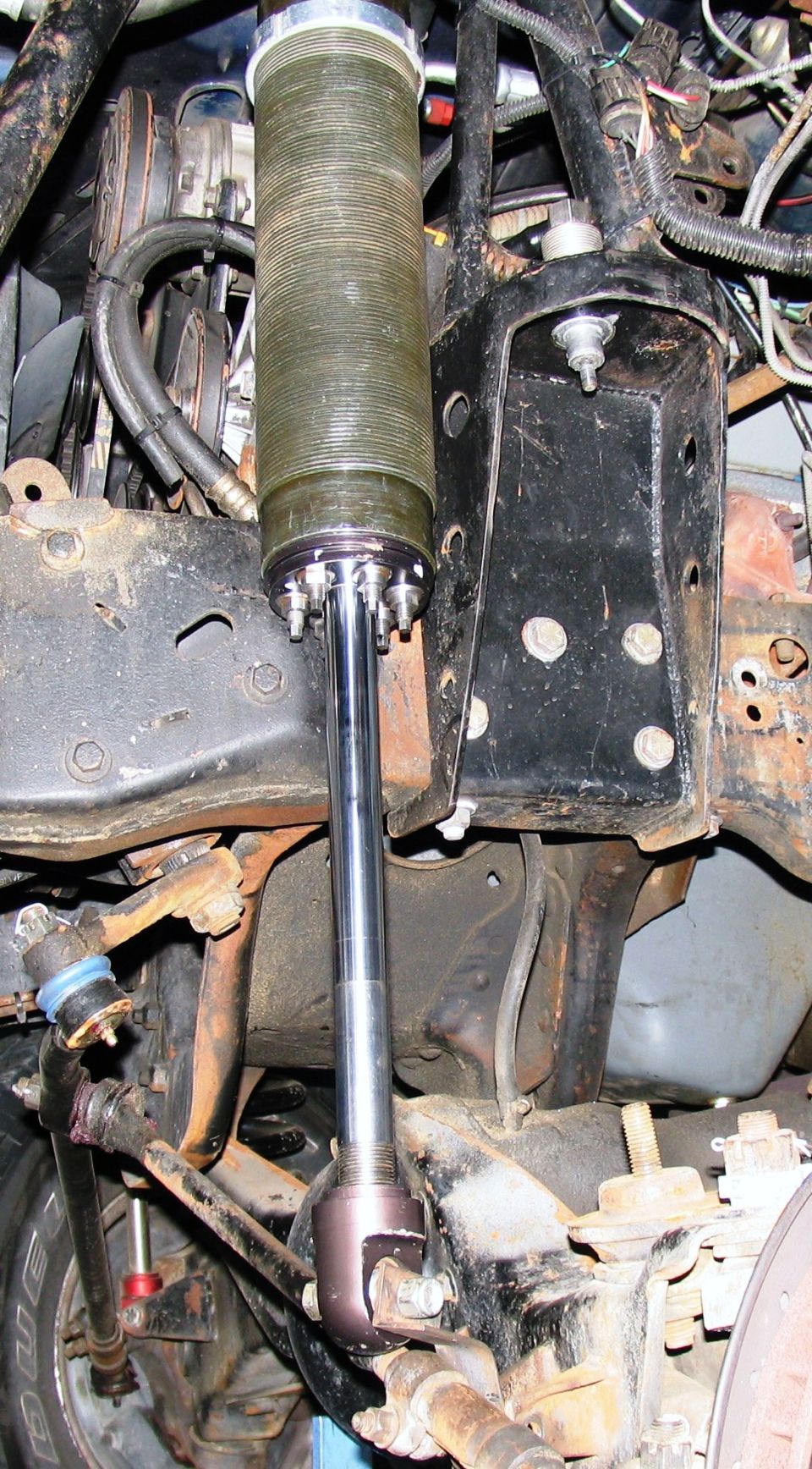 Custom shock absorber assembly with ribbed reservoir, attached to black metal bracket and suspension linkage