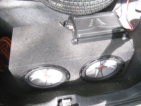 1997 Ford Crown Victoria - Car trunk audio setup with subwoofers and amplifier. Spare tire is also visible.