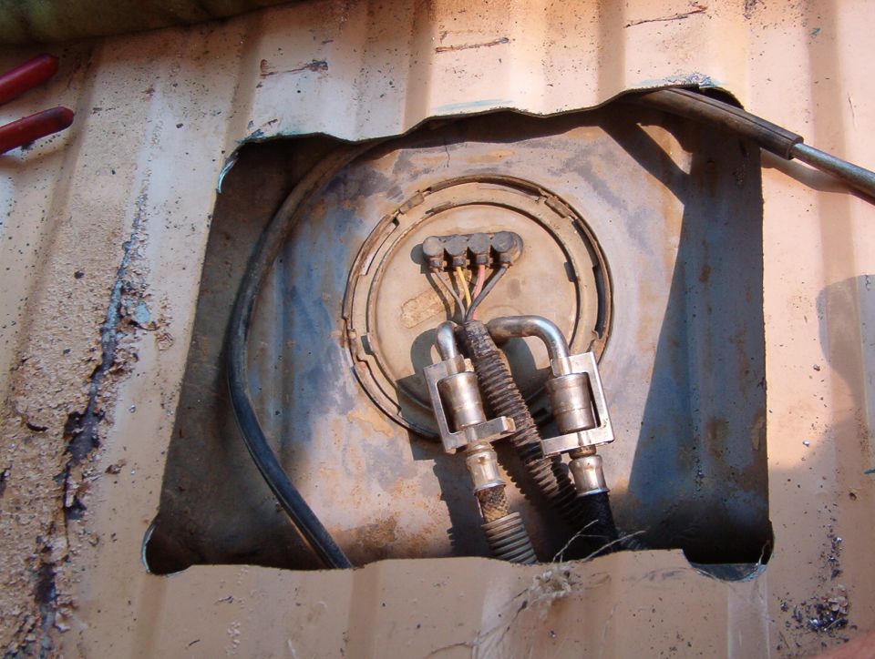 Fuel sender opening cut into top of a rusty steel fuel tank