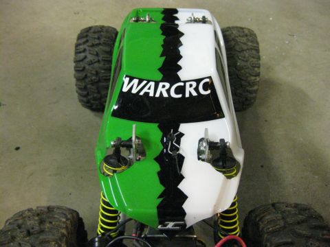 2010 Ford Pickup - A remote control car with a distinctive green and white body is viewed from the front, showing its tires and suspension.