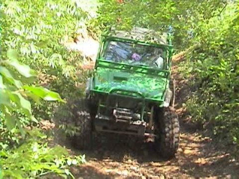 1992 Ford Bronco - Off-road vehicle navigates a wooded trail, kicking up dust.