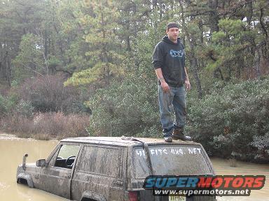 2005 Ford Excursion - A man stands atop a mud-splattered Jeep Cherokee XJ stuck in a muddy body of water.