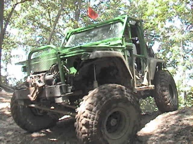 Green off-road vehicle with large tires on a dirt trail
