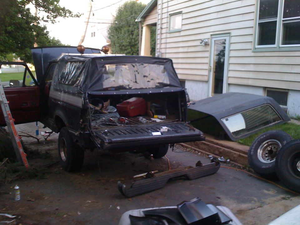 Black soft top Bronco with open tailgate and removed hardtop nearby