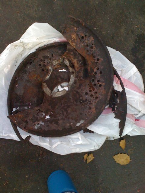 1988 Ford Bronco - A severely corroded brake rotor, likely a vehicle part, is shown on a white plastic bag.