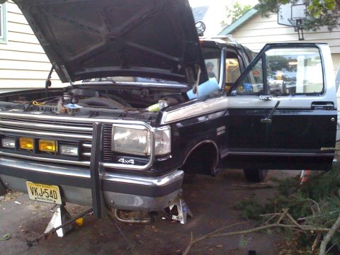 1988 Ford Bronco - This 1988 Ford Bronco is shown with its hood and driver door open, elevated on jack stands for maintenance.