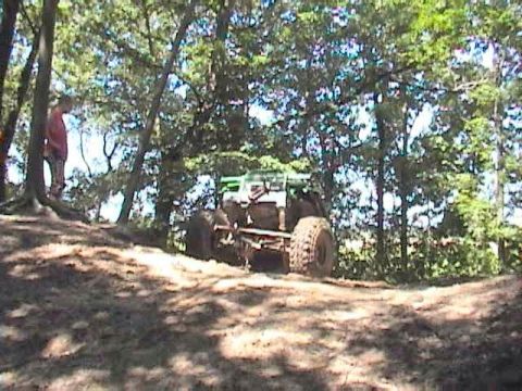 1992 Ford Bronco - An off-road vehicle navigates a wooded trail, its large tires visible on the side.