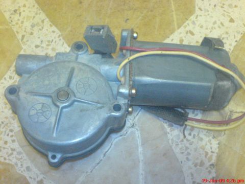 1992 Ford Crown Victoria - Disassembled window motor assembly with red and yellow wires, likely for a car door.